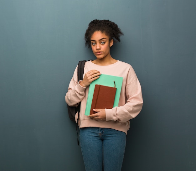 Donna di colore del giovane studente che guarda avanti diritto. Tiene dei libri.