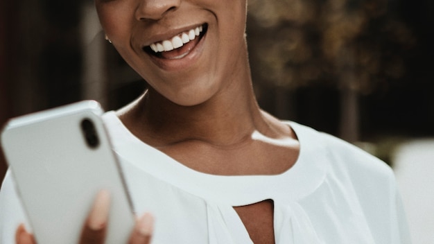 Donna di colore felice sul suo telefono