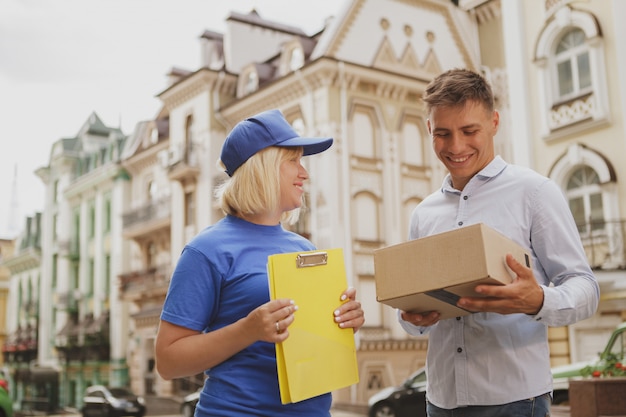 Donna di consegna amichevole in uniforme blu sulla strada della città