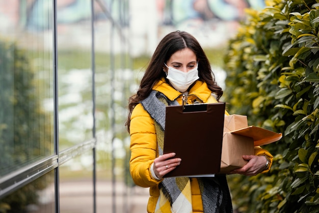 Donna di consegna con maschera che trasporta pacchetto