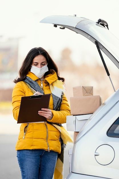 Donna di consegna con maschera che trasporta pacchetto