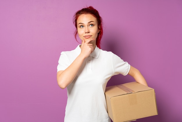 Donna di consegna dell'adolescente isolata sulla parete viola che pensa un'idea mentre osservando in su