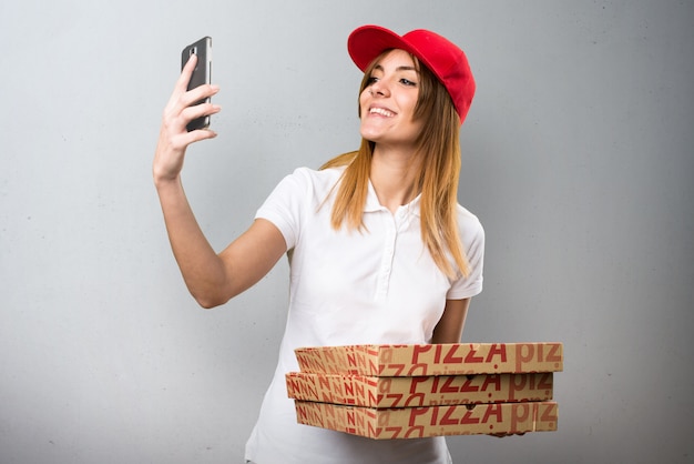 Donna di consegna della pizza che fa un selfie su priorità bassa strutturata