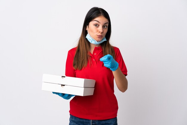 Donna di consegna della pizza che tiene una pizza isolata su fondo bianco sorpreso e che indica davanti