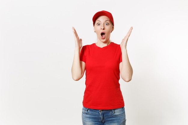 Donna di consegna in uniforme rossa isolata su fondo bianco. Donna scioccata professionale in berretto, t-shirt, jeans che lavora come corriere o rivenditore, tenendosi per mano vicino al gesto del viso. Copia spazio, pubblicità.