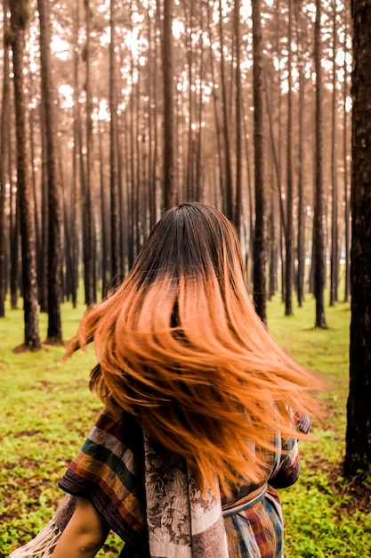 Donna di felicità che passa rapidamente i suoi capelli in una foresta