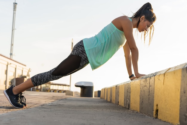 Donna di forma fisica che fa flessioni Vista laterale di sera d'estate di allenamento di allenamento all'aperto. Concetto di sport stile di vita sano