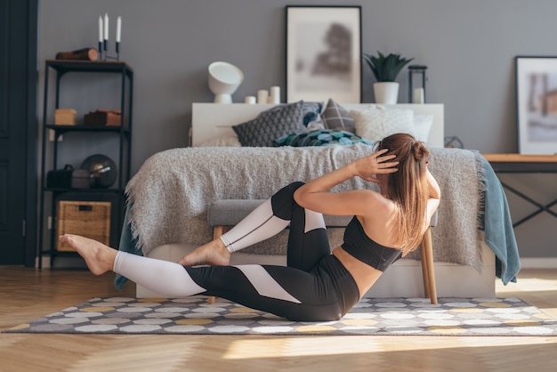 Donna di forma fisica che lavora a casa facendo esercizi addominali di torsioni.