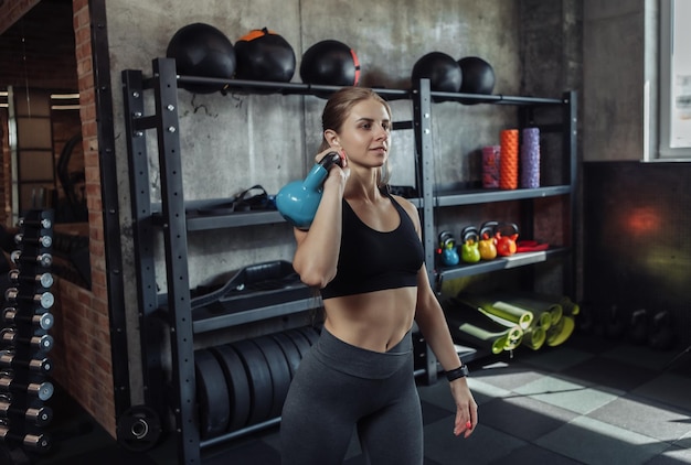 Donna di forma fisica di bellezza che si esercita con il kettlebell alla palestra moderna