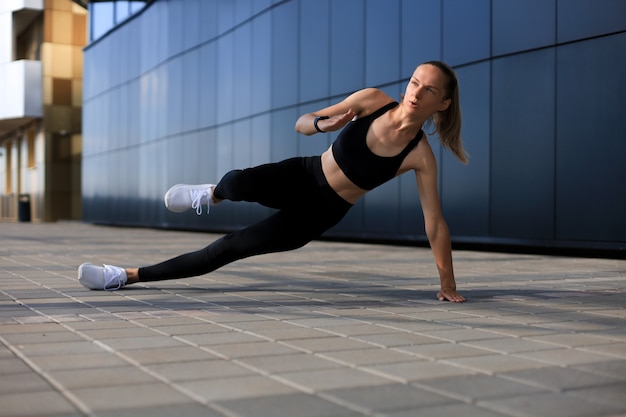 Donna di forma fisica in abiti sportivi che fa esercizio della plancia laterale all'aperto.