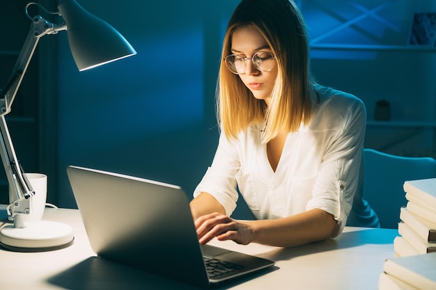 Donna di lavoro a distanza di lavoro notturno che utilizza il laptop