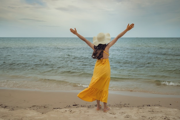 Donna di libertà con le braccia alzate sulla spiaggia del mare con il colpo di vento