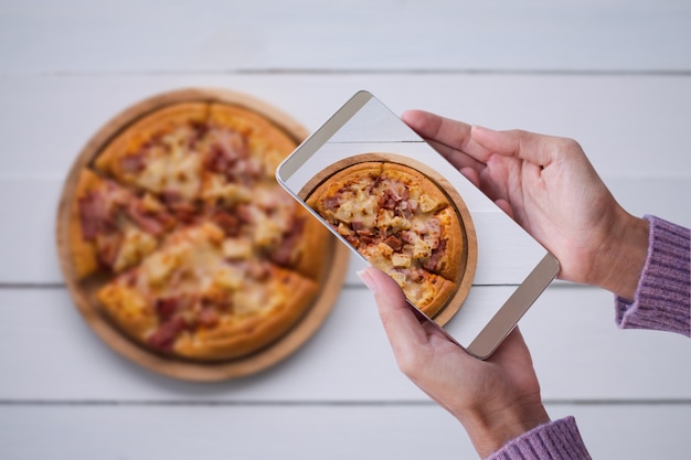 Donna di mano con pizza fotografia maglione con smartphone. fast food e concetto di tecnologia.