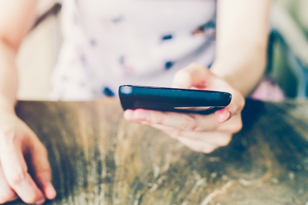 Donna di mano utilizzando il telefono in caffè con profondità di campo.