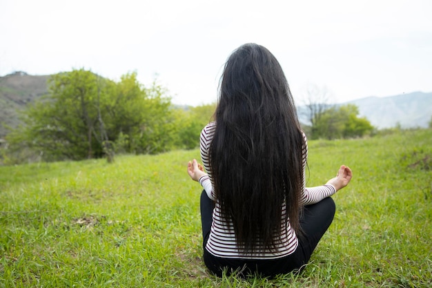 Donna di meditazione che si siede nell'erba verde