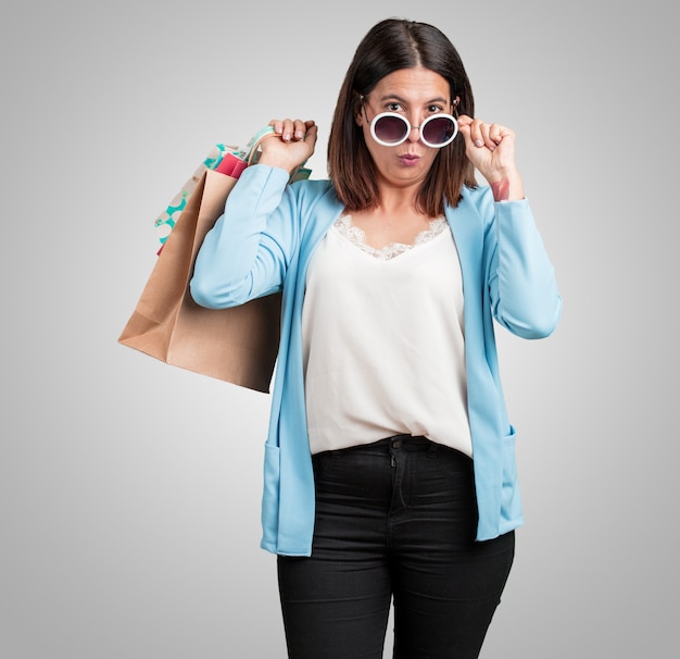 Donna di mezza età allegra e sorridente, molto eccitata portando una shopping bag