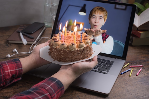 Donna di mezza età asiatica sentirsi felici mentre celebra il compleanno virtuale tramite videochiamata