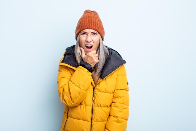 Donna di mezza età capelli grigi con la bocca e gli occhi spalancati e la mano sul mento. concetto di tempo freddo