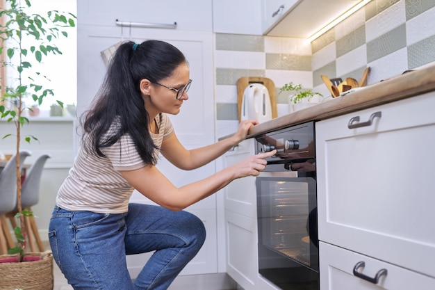 Donna di mezza età che cucina torta al forno a casa in cucina