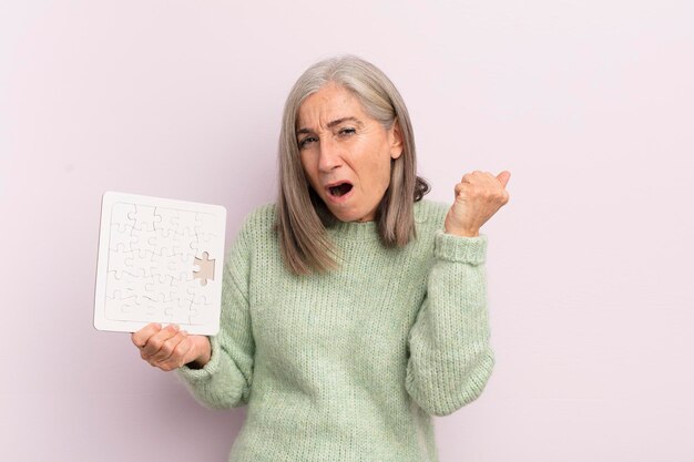 Donna di mezza età che grida in modo aggressivo con un concetto di sfida di puzzle di espressione arrabbiata