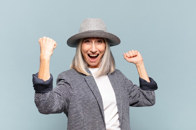 Donna di mezza età che grida trionfante, guardando come vincitore eccitato, felice e sorpreso, celebrando