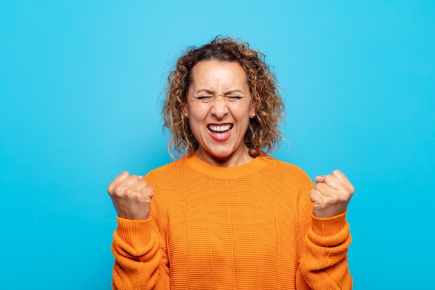 Donna di mezza età che grida trionfante, ride e si sente felice ed eccitata mentre celebra il successo