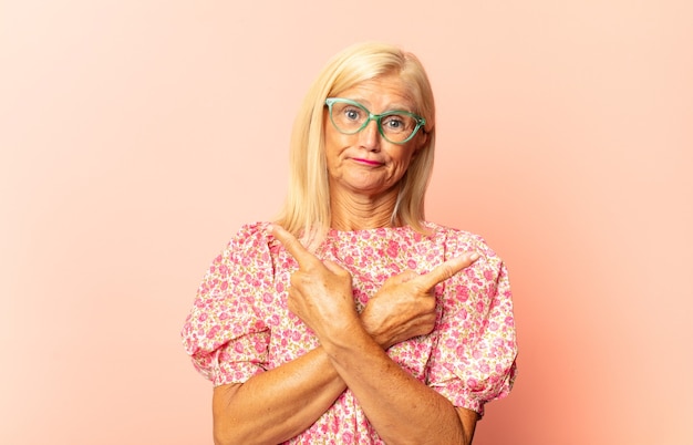 Donna di mezza età che incornicia o delinea il proprio sorriso con entrambe le mani, guardando positivo e felice, concetto di benessere