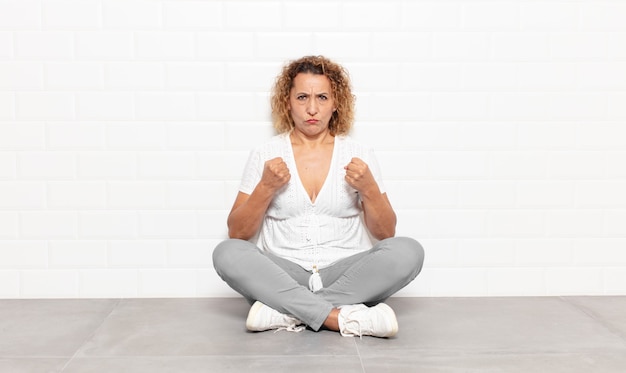 Donna di mezza età che sembra sicura, arrabbiata, forte e aggressiva, con i pugni pronti a combattere in posizione di boxe