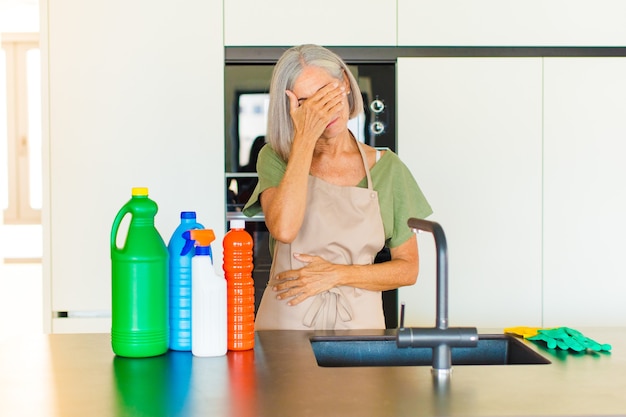 Donna di mezza età che sembra stressata, vergognosa o turbata, con mal di testa, coprendosi il viso con la mano