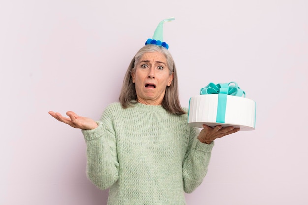 Donna di mezza età che si sente estremamente scioccata e sorpresa concetto di torta di compleanno
