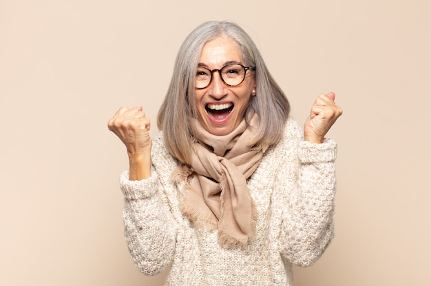 Donna di mezza età che si sente felice, sorpresa e orgogliosa, grida e celebra il successo con un grande sorriso