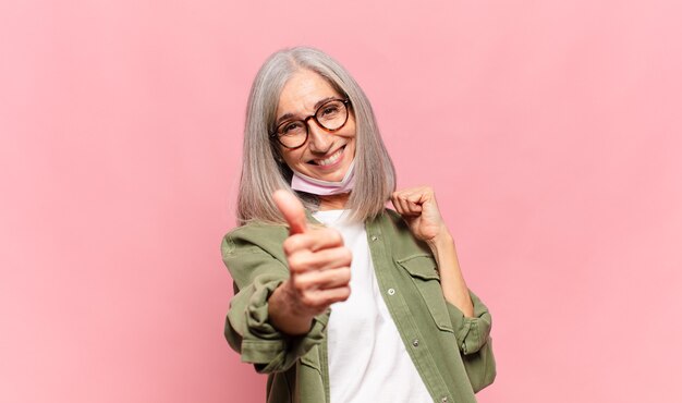 Donna di mezza età che si sente orgogliosa, spensierata, sicura e felice, sorridendo positivamente con i pollici in su