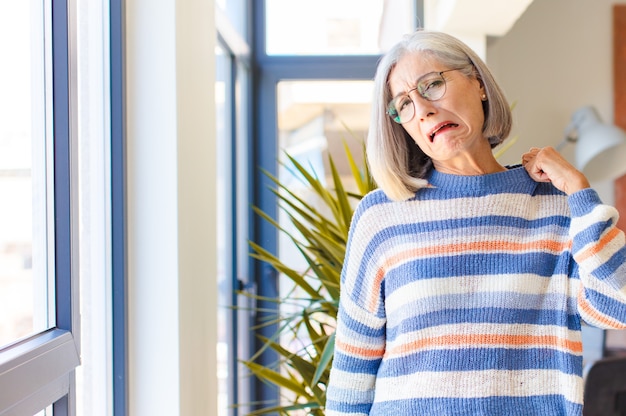 Donna di mezza età che si sente stressata, ansiosa, stanca e frustrata, tira il collo della camicia, sembra frustrata dal problema