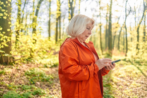 Donna di mezza età che tiene il cellulare in mano all'aperto bella donna matura in verde sportivo noi