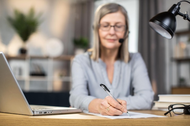 Donna di mezza età che tiene una conferenza online al lavoro remoto