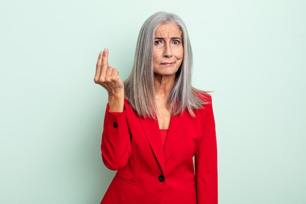 Donna di mezza età con capelli grigi che fa un gesto capice o denaro, dicendoti di pagare. concetto di donna d'affari senior