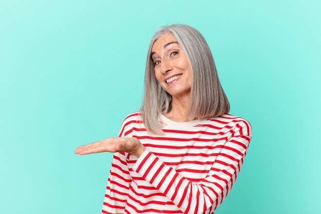 Donna di mezza età con i capelli bianchi che sorride allegramente, si sente felice e mostra un concetto