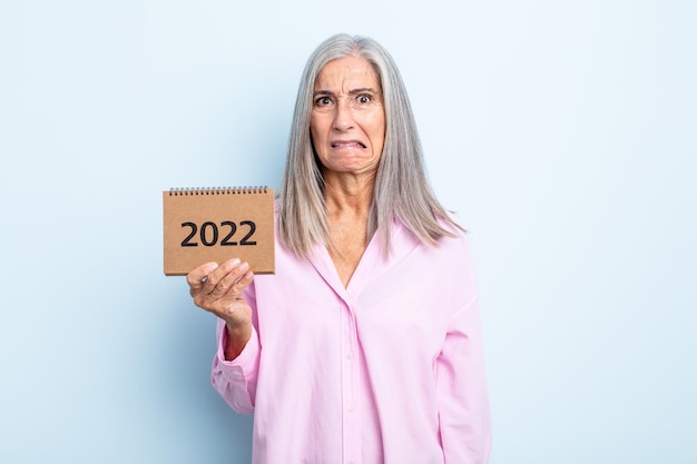 Donna di mezza età con i capelli grigi che sembra perplessa e confusa. concetto di calendario 2022