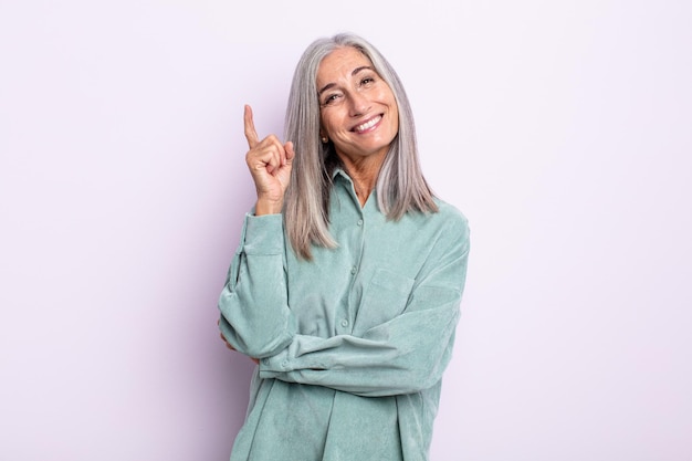 Donna di mezza età con i capelli grigi che sorride felicemente e guarda di traverso, chiedendosi, pensando o avendo un'idea