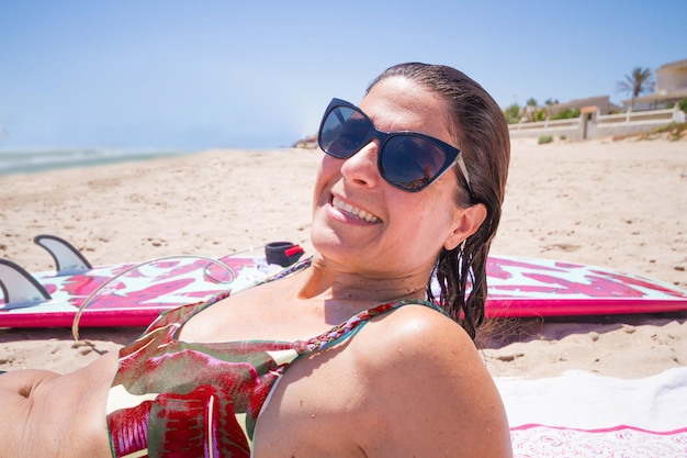 Donna di mezza età felice attraente con gli occhiali sulla spiaggia