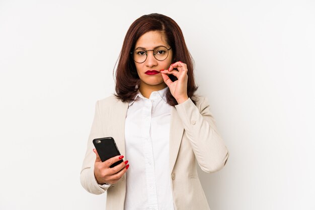 Donna di mezza età in possesso di un telefono cellulare con le dita sulle labbra mantenendo un segreto