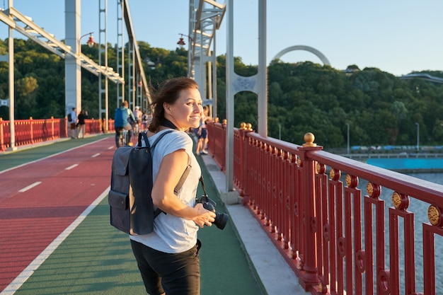 Donna di mezza età positiva che cammina sul ponte