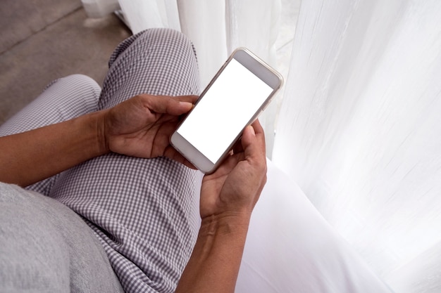 donna di mezza età utilizzando smart phone nel letto, vista dall&#39;alto.