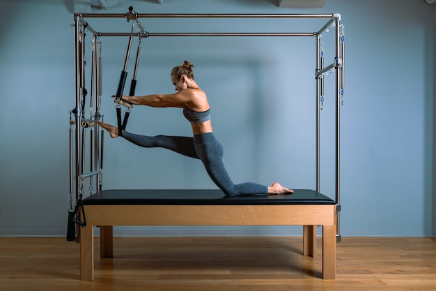 Donna di Pilates in esercizio teaser riformatore in palestra al chiuso