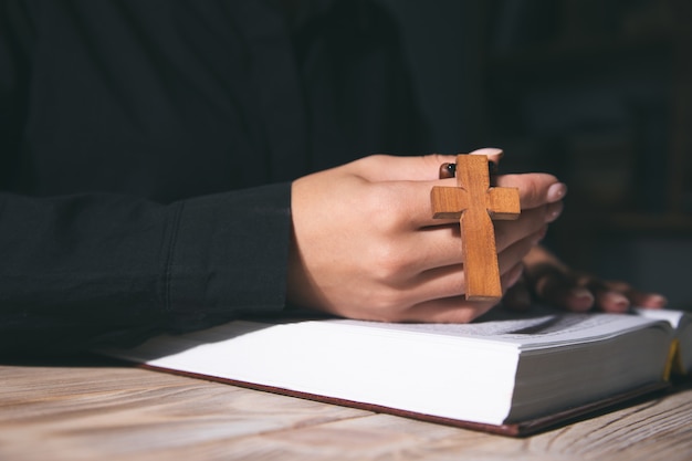 Donna di preghiera che tiene la croce sulla Sacra Bibbia