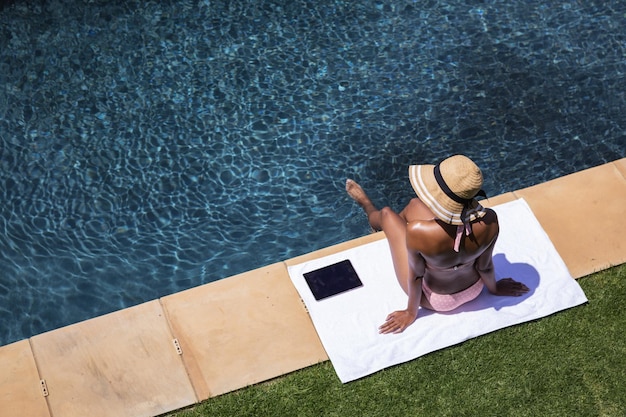 Donna di razza mista che trascorre del tempo a casa, rilassandosi e prendendo il sole in piscina. Autoisolamento e distanza sociale durante il blocco della quarantena durante l'epidemia di coronavirus covid 19.