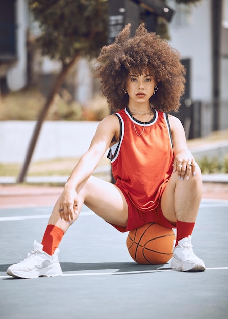 Donna di razza mista in posa su un campo da basket. Bellissimo giocatore di basket in posa con sicurezza all'esterno.