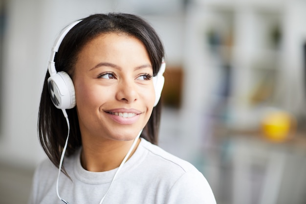 Donna di razza mista sorridente che ascolta la musica