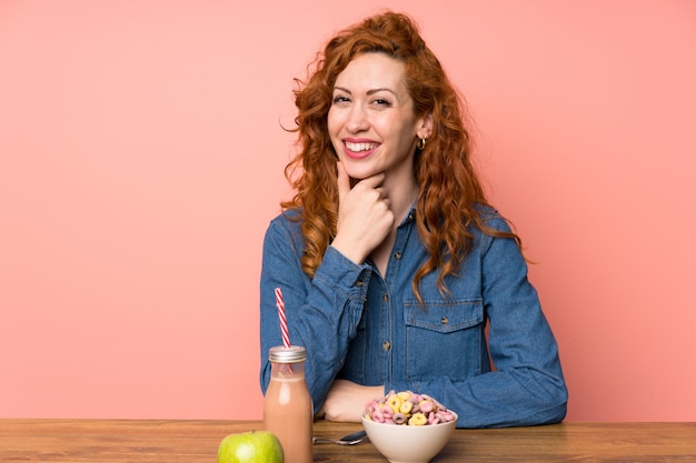 Donna di Redhead che mangia i cereali da prima colazione e la risata della frutta