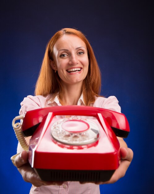 Donna di Redhead con telefono rosso